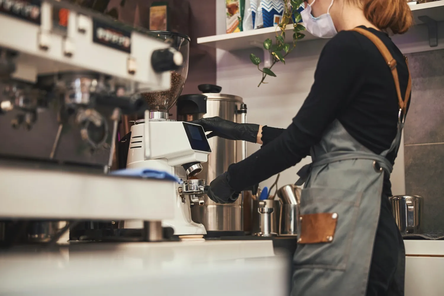A barista grinding fresh coffee at an espresso machine