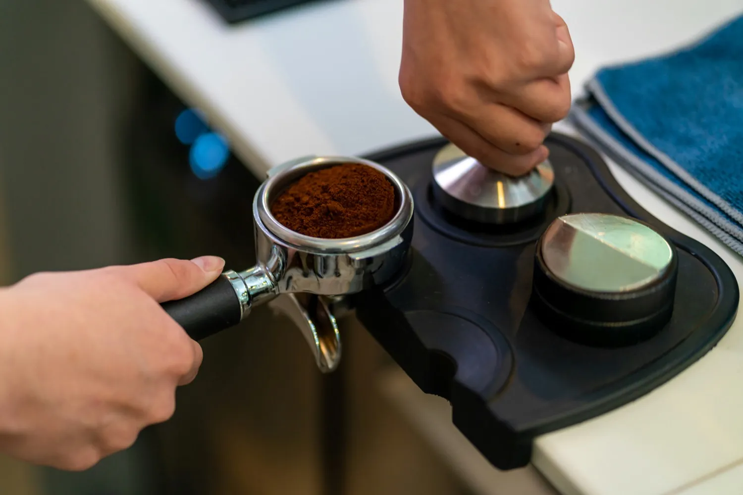 A barista tamping a portafilter at a leveling station